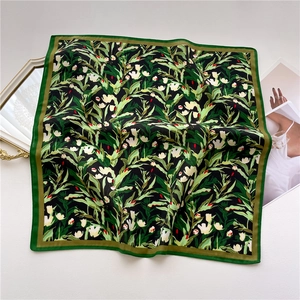 Detailed close-up of floral square scarf with green leaves and silky satin texture