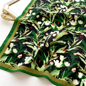 Detail of floral silk scarf with black tulip pattern and green herringbone texture