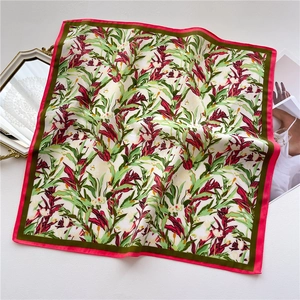 Detailed flat lay of floral square scarf with red tropical blooms and pink borders
