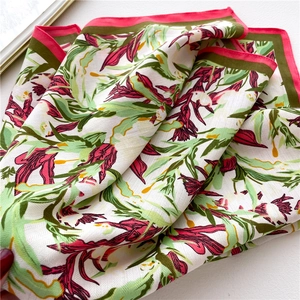Close-up of floral silk scarf with tropical pattern and green pink rolled edges