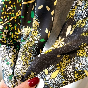 Macro detail of high-quality floral print on soft black satin fabric with elegant drape