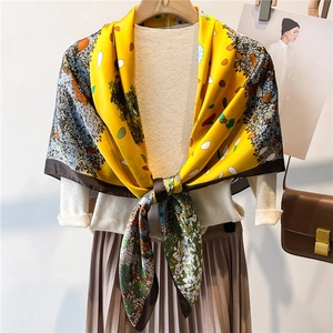 Detail of a silky yellow floral 110cm square scarf draped on a mannequin with classic motifs