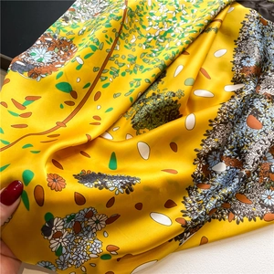 Detailed close-up showing the smooth satin texture and floral print of the large yellow scarf