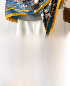 Detail of blue and yellow floral silk scarf with magnolia pattern on a model