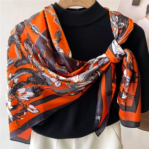 Detail of silk satin scarf with vibrant orange abstract floral pattern and rolled edges