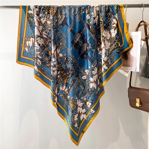 Detailed drape of blue floral silk scarf featuring yellow borders and magnolia patterns