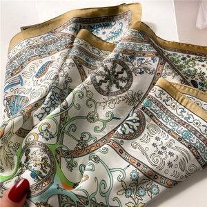 Close-up of geometric floral silk scarf with golden edges and vine pattern