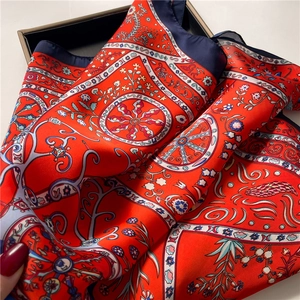Detail of red floral satin scarf with intricate wheel patterns and blue border in box