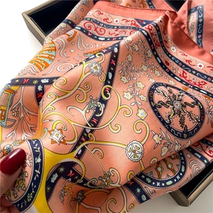Detail of bohemian floral pattern on orange silk scarf with geometric border