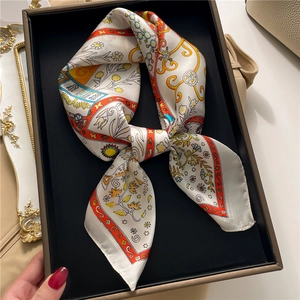 Close-up of a floral geometric silk scarf tied in a bow inside a premium black gift box