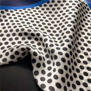 Close-up of silk-textured square scarf with black polka dots and blue edge detailing