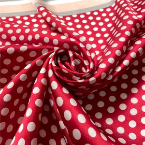 Macro shot of red silk-like scarf featuring white polka dots and smooth satin texture