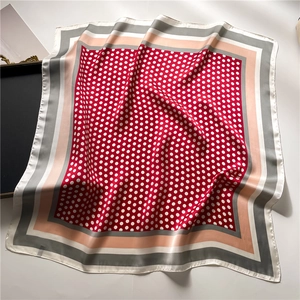 Silk-feel square scarf featuring red polka dots and geometric borders on a light surface