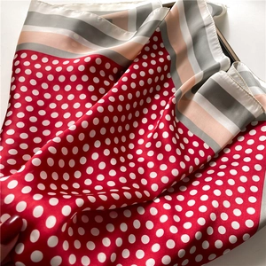 Close-up of red polka dot silk scarf with striped borders and smooth satin texture