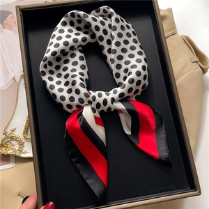 Detailed close-up of a knotted silk scarf with black polka dots and red stripe accents