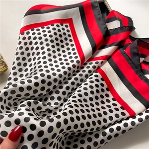 Detailed view of silk-like scarf featuring red black white stripes and polka dot pattern