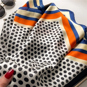 Detail of silk-like polka dot scarf showing soft texture with hand and sunglasses
