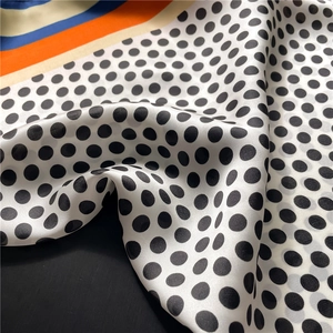 Close-up of geometric silk scarf showing smooth satin texture and colorful stripes