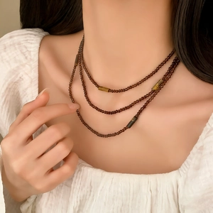 Retro multi-layered beaded necklace with cylinder tiger eye stones on a white fabric background