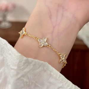 Elegant gold clover bracelet with inlaid zircons shown on a female wrist in soft light
