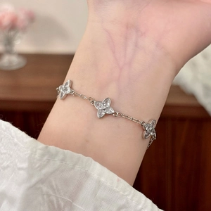 Elegant silver four-leaf clover bracelet with sparkling zircons on a woman's wrist