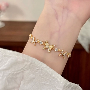 Elegant gold butterfly bracelet with white zircon stones on woman wrist in soft light