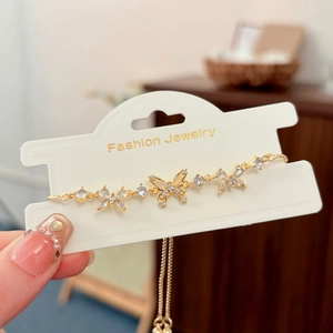 Detail of adjustable gold butterfly bracelet with crystal accents on a display card