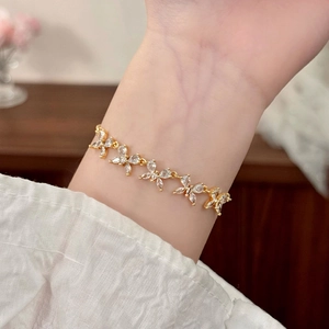 Elegante bracciale a farfalla dorato con pietre di zirconia marquise al polso di una donna