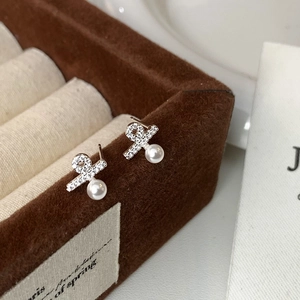 Macro detail of elegant silver pearl earrings with micro-set diamonds on velvet box