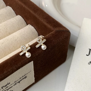 Detailed close-up of pearl stud earrings with sparkling cubic zirconia on a jewelry box