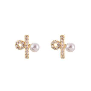 Detailed macro view of gold pearl earrings with pave zircons and geometric accents