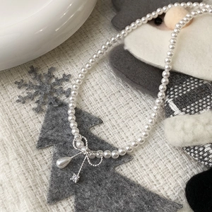 Elegant pearl bow necklace with droplet pendant displayed on a winter festive background