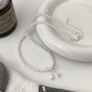Detail of pearl necklace featuring a bow pendant with teardrop pearl and zircon accents