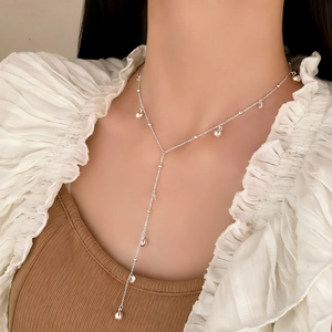 Collana lunga a Y in argento minimalista con perline metalliche indossata da modella