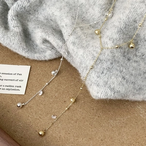 Eleganti collane lunghe in oro e argento con gocce di cristallo su sfondo in maglia
