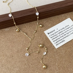 Dettaglio della collana a catena dorata con sfere lucide e pietre di zircone trasparente