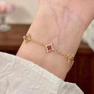Close-up of gold star bracelet with pink gems and zircons worn on a female wrist