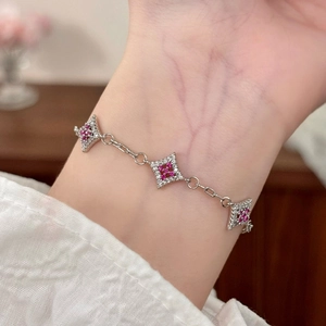 Detail of silver bracelet featuring hollow diamond charms with rubies and zircons