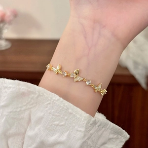 Bracelet papillon doré élégant avec zircon et nacre porté délicatement au poignet