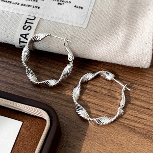 Macro view of silver twisted rope textured hoop earrings with a polished metallic finish