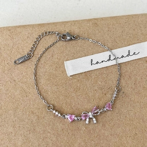 Bracelet en acier inoxydable avec cœurs en cristal rose et nœud sur fond de papier kraft