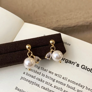 Detail of elegant gold-plated earrings with white pearl and teardrop zircon crystal