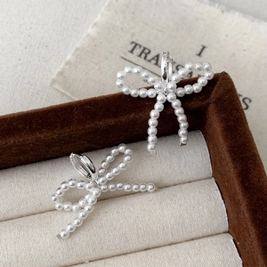French style pearl bow earrings with silver hoops displayed on a brown jewelry box