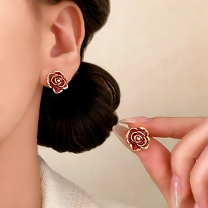 Elegant vintage red rose stud earrings with gold edges worn by a model