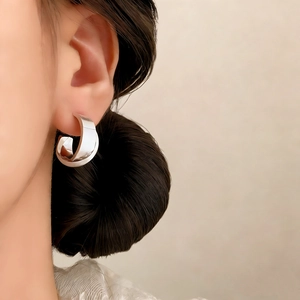 Silver wide C-shape polished metal earrings shown on a model with a minimalist style