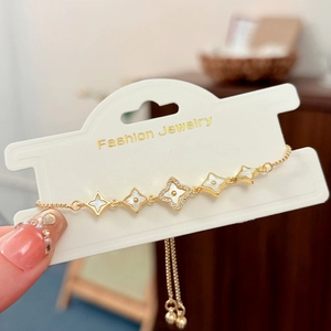 Detail of adjustable gold bracelet with clover charms and white mother of pearl inlay