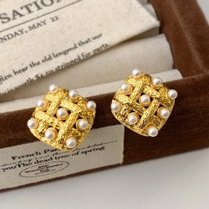 Elegant gold woven square stud earrings with embedded pearls in a velvet jewelry box
