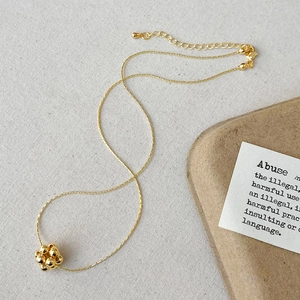 Détail macro du pendentif à boules dorées polies avec sa chaîne fine et élégante