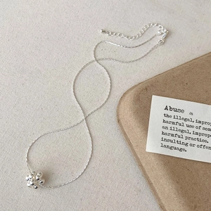 Gros plan du collier à pendentif grappe de boules argentées sur fond de lin naturel