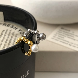Elegant gold and silver ear cuffs with pearls and crystals hanging on a candle cup